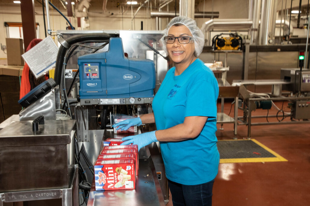 A smiling Joy Cone working sorts product boxes. 